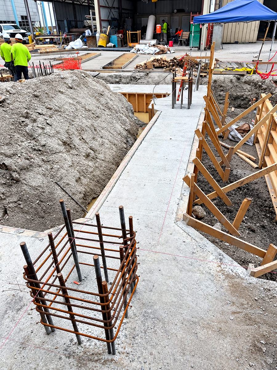 Braced stem wall forms along the foundation line with vertical rebar dowels for a column pier