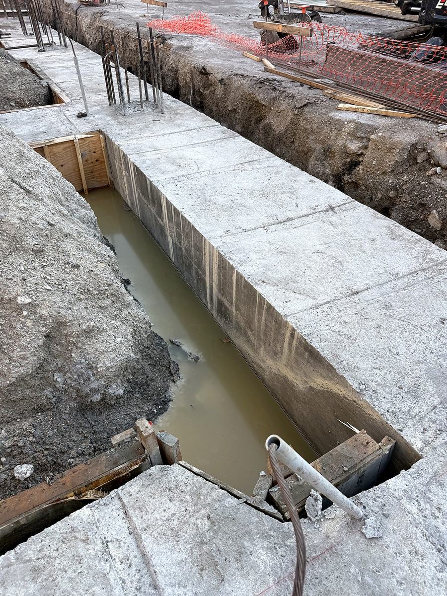 Poured concrete stem wall with forms stripped and rebar dowels projecting for the next pour
